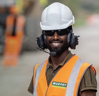 A Murphy colleague smiling at the camera, wearing protective gear and a communications headset.