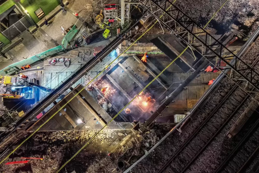 A railway bridge construction site from above with people working on a section of the bridge.