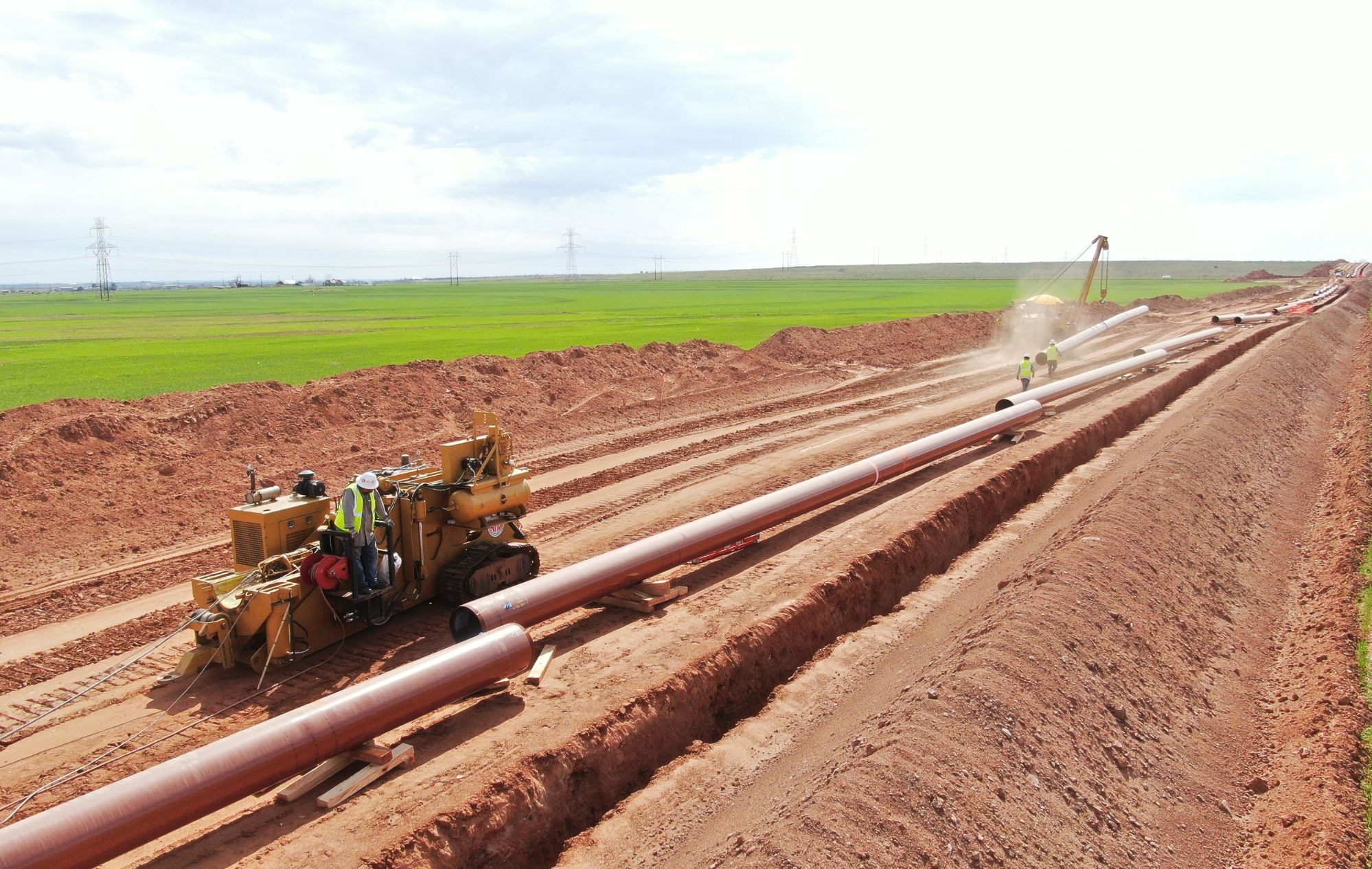 People wearing safety uniform installing large pipes into the ground.