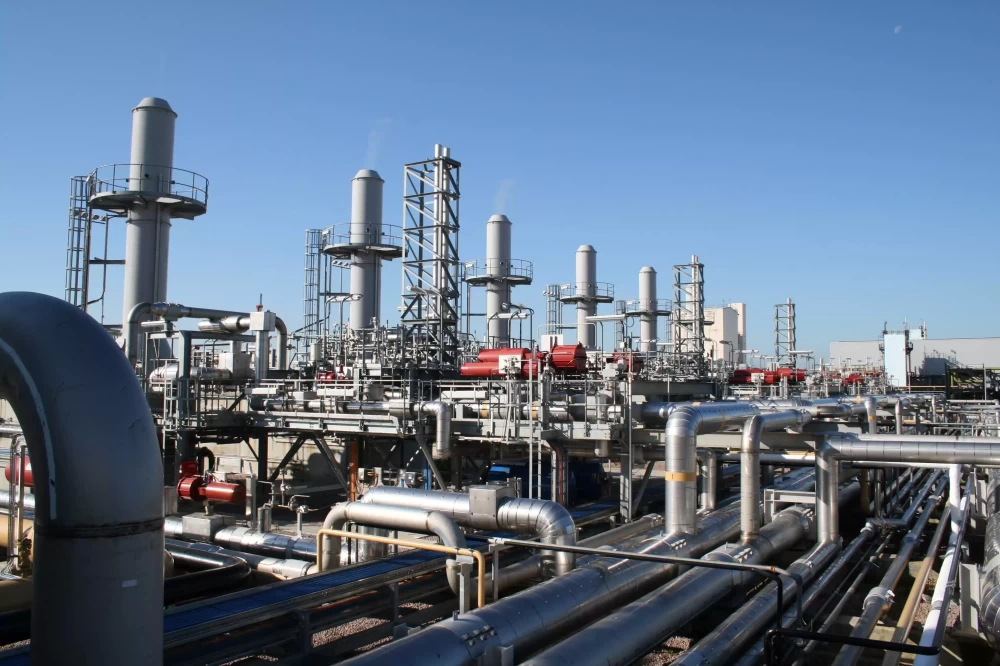 An liquefied natural gas terminal with metal pipes on a bright day.