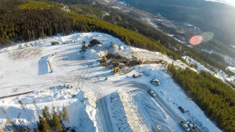 An aerial view of a construction site surrounded by trees in the mountains in Canada.