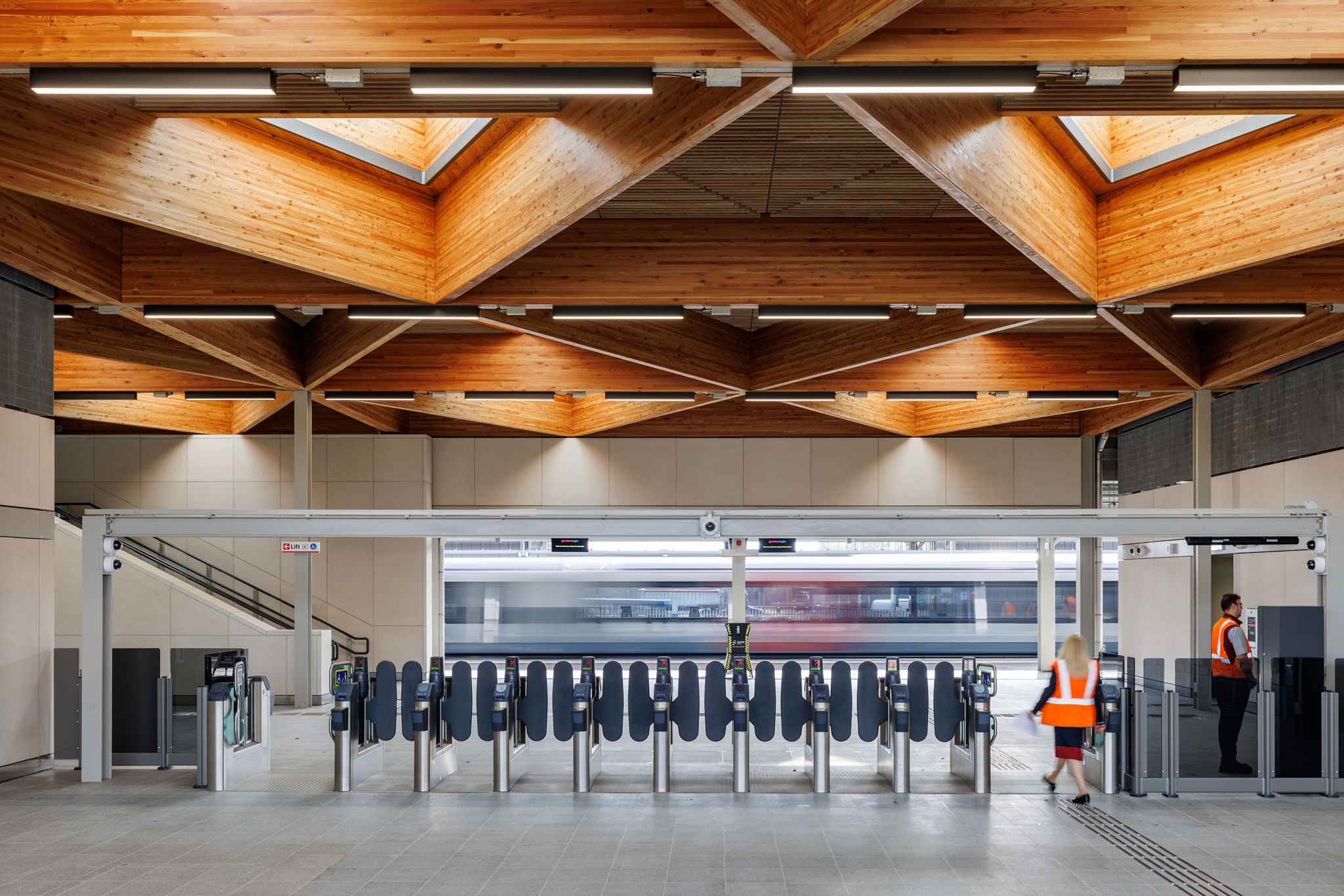 Train station ticket gates with a train at a platform in the background.