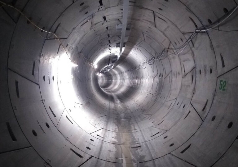 The inside of a concrete power tunnel with wires on the walls.