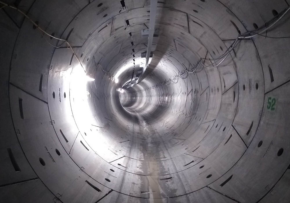 The inside of a concrete power tunnel with wires on the walls.
