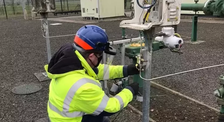 A person wearing safety equipment and high-visibility jacket working on a gas pipeline.