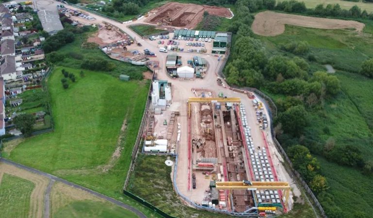 An aerial view of a relief sewer construction site surrounded by fields and houses.