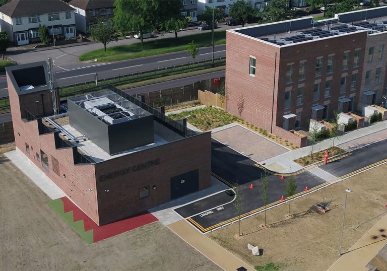 An aerial view of residential flats and an energy centre next to a road.