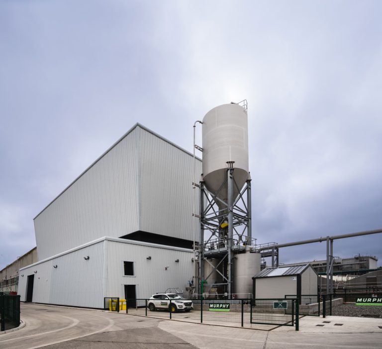 A grey building at a wastewater treatment plant with a black fence with a Murphy sign.