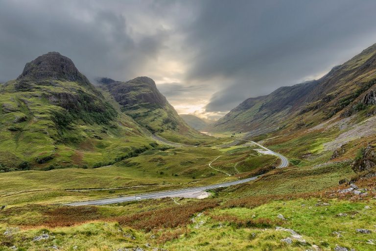 A road in Scotland in between grass covered hills.
