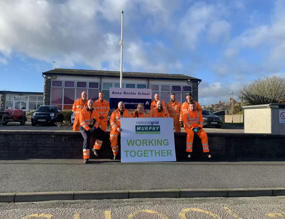 A group of Murphy employees sat on a wall outside a school.