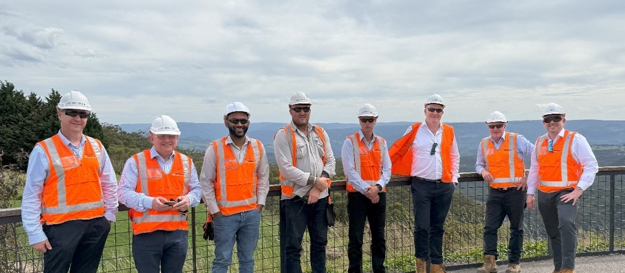 Members of the Murphy and Abergeldie teams wearing orange high-visibility jackets and helmets outside on a visit to Australia.