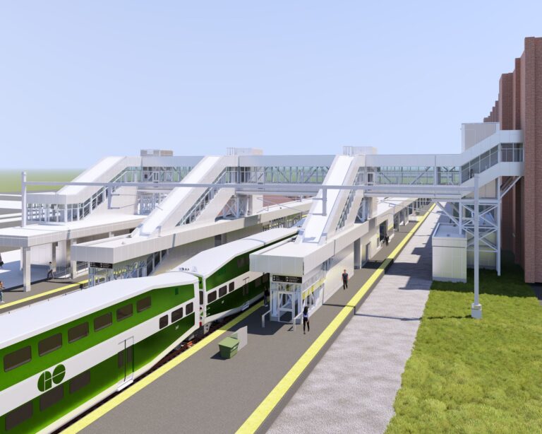 A rendering of railway station with a green train at a platform and enclosed bridge connecting the platforms and the station building